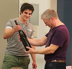 Student und Mann betrachten Weinflasche