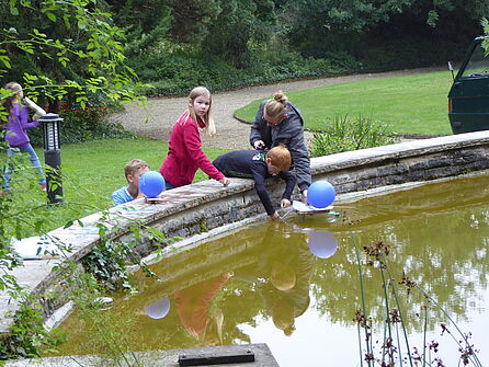 Kinder spielen mit Lufballonen am Teich