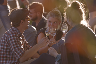 Eine Gruppe junger Menschen sitzt zusammen und stößt mit Wein an. © Hochschschule Geisenheim